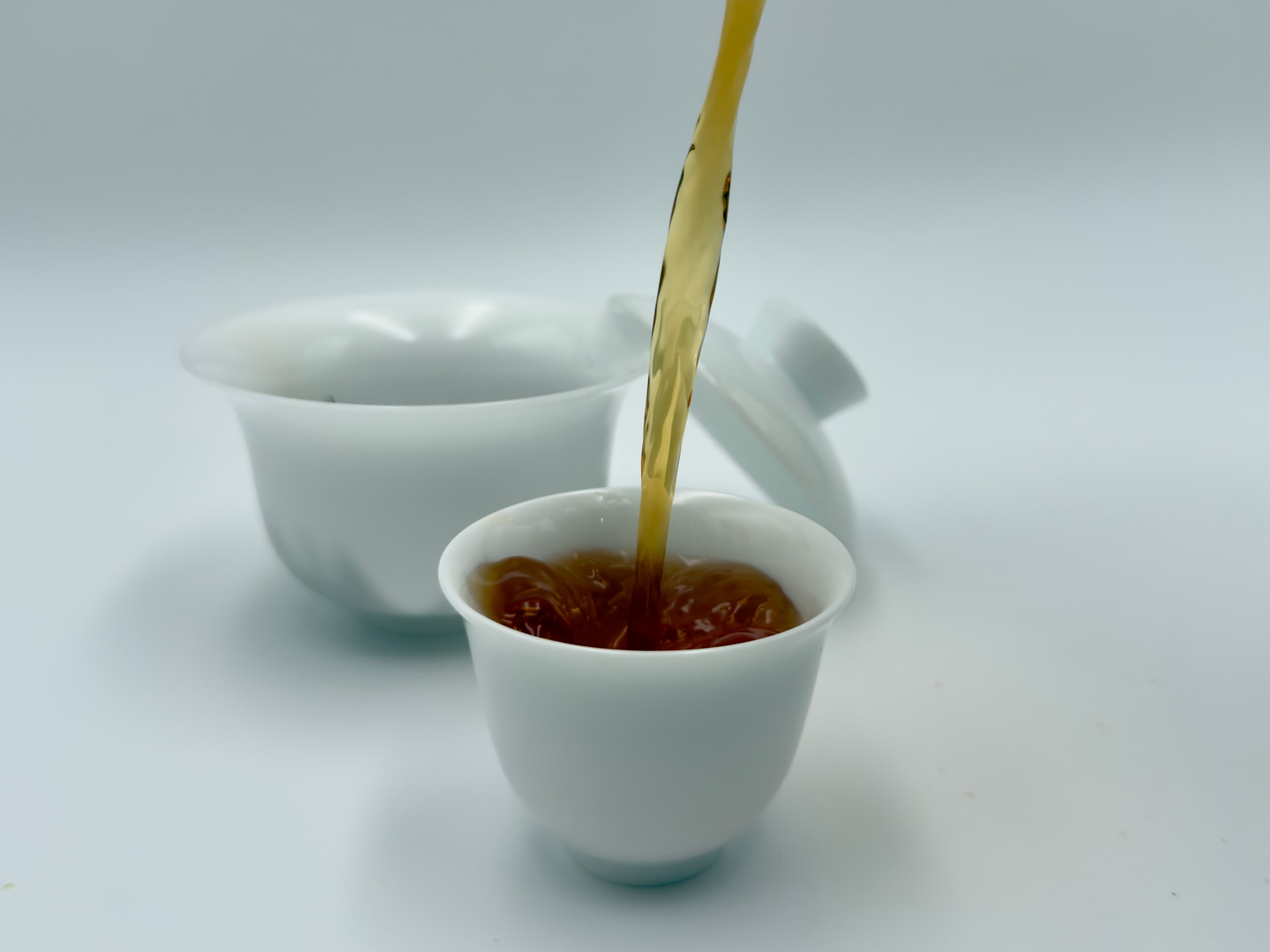Golden Eyebrow's golden-amber liquor being poured gongfu-style into small cups